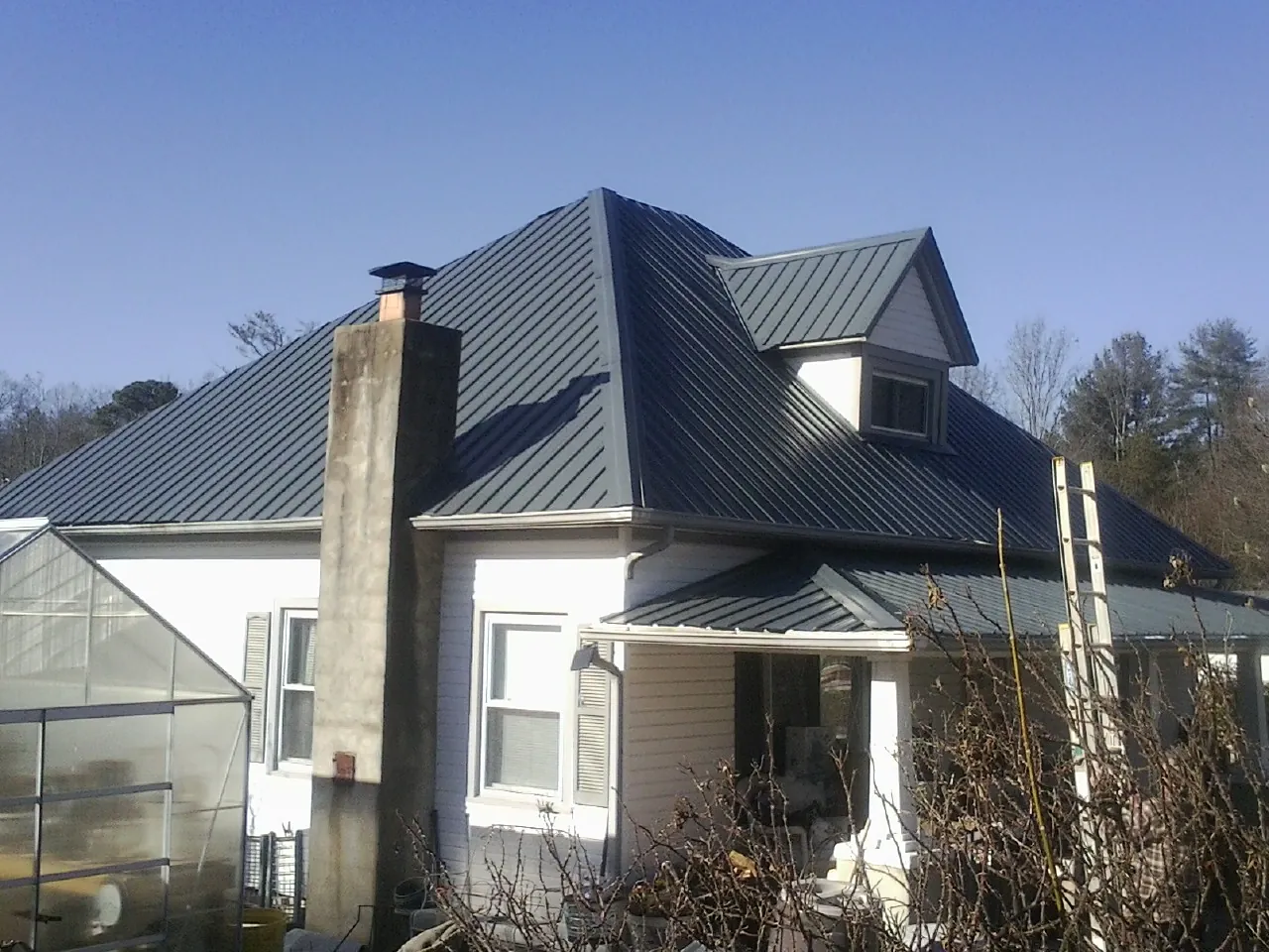 Dark blue standing seam metal roof on a white farmhouse with dormer — Slate & Tile Roof Repair by Roofing Brothers in Sevierville