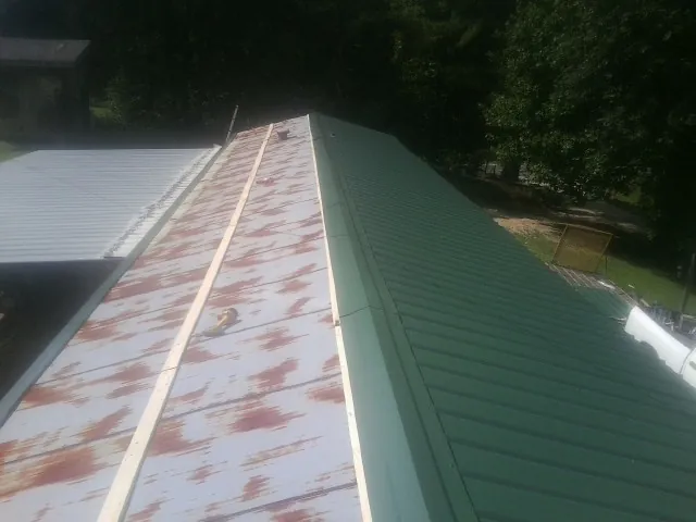 Old rusted panels beside newly installed green metal roofing — Wind Damage Roof Repair by Roofing Brothers in Sevierville