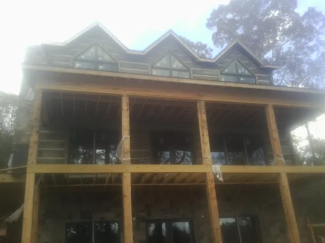 Dormers and porch framing on a large log home under construction — Roof Coating work by our crew in Sevierville