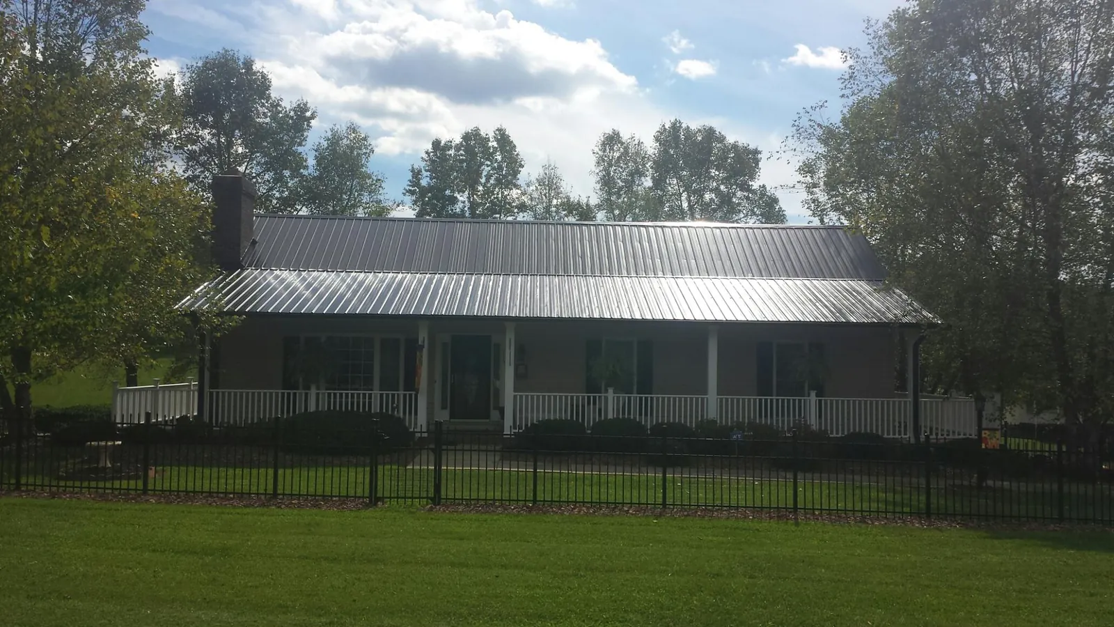 Gray metal roof on a brick ranch with a full width front porch — Gutter Guard Installation work by our crew in Sevierville