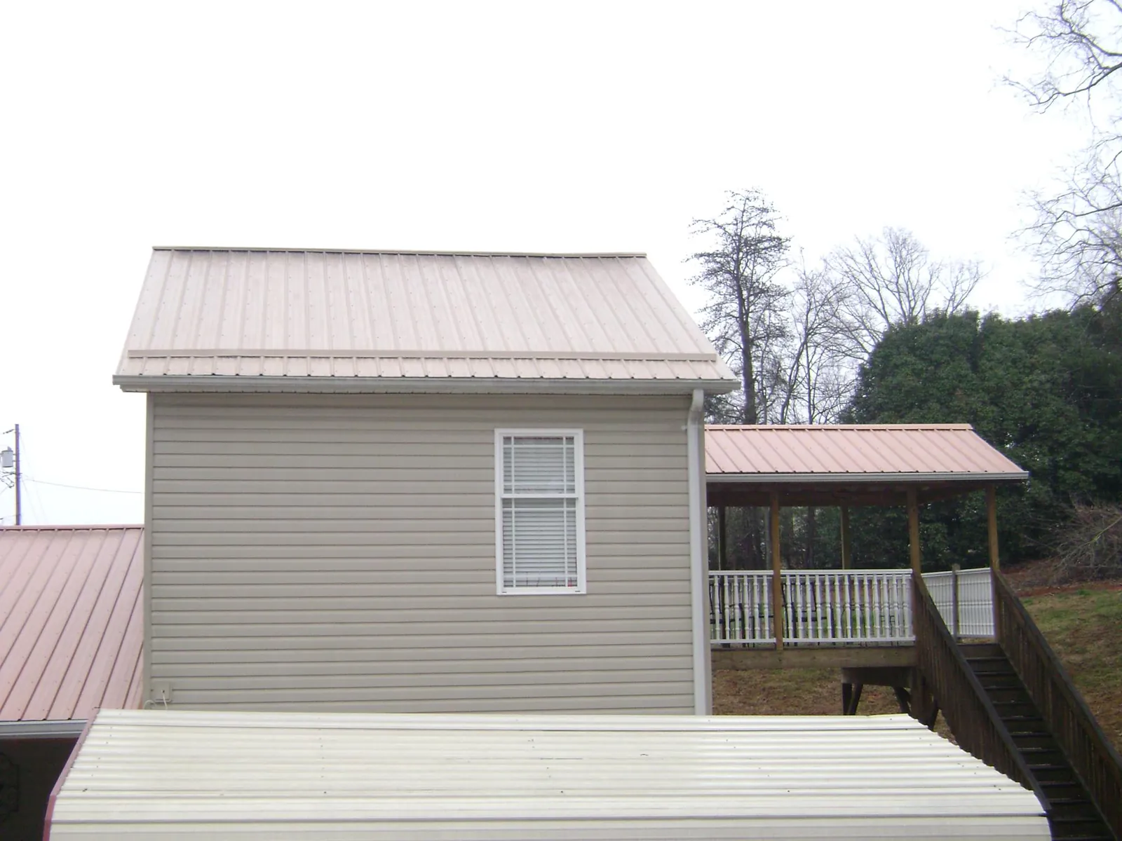 Tan metal roofs on a two story addition and attached porch, from a Roof Replacement job in Sevierville