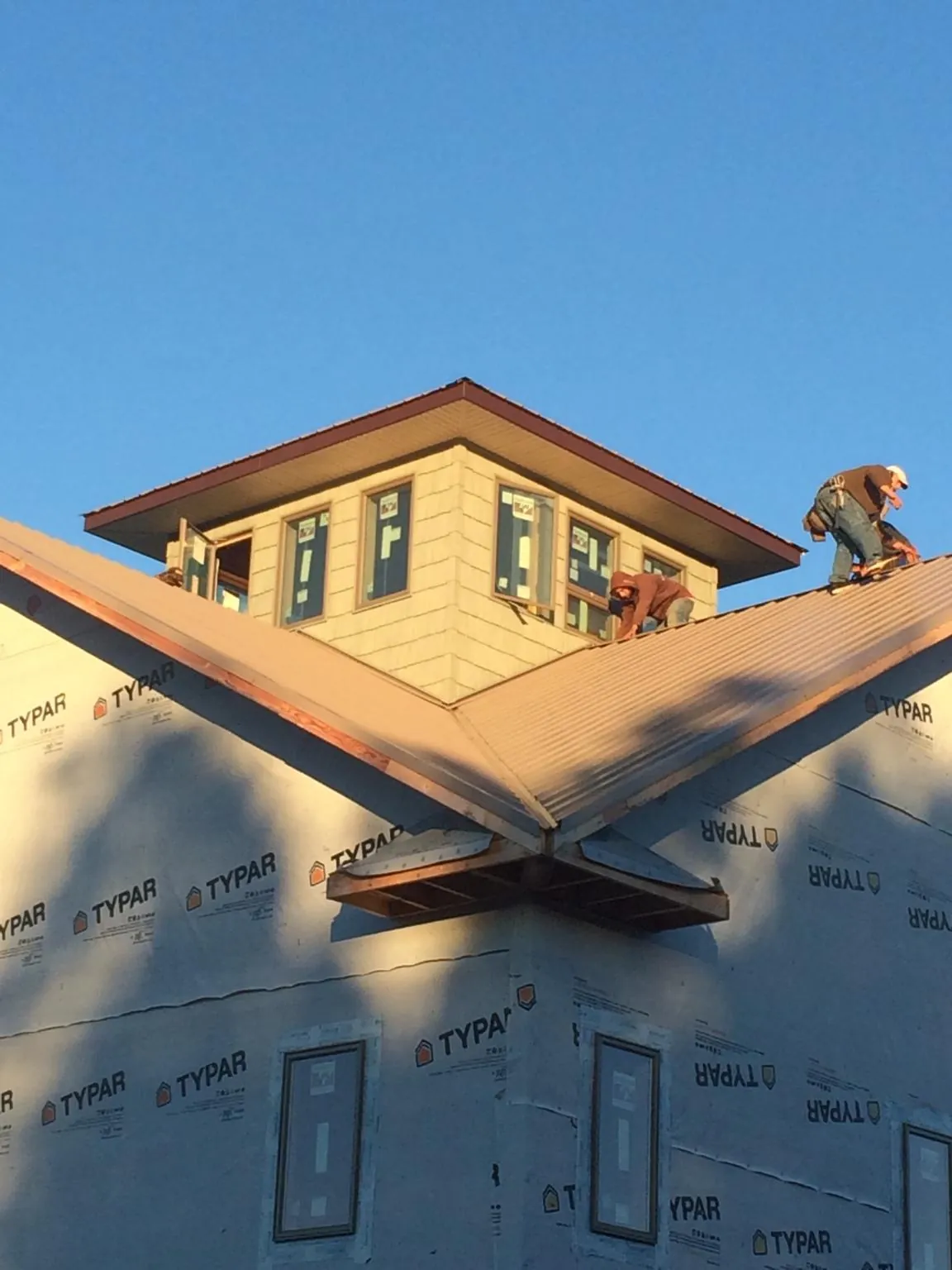 Roofers working around a rooftop cupola on a new metal roof at sunset — Roof Waterproofing in Sevierville by Roofing Brothers